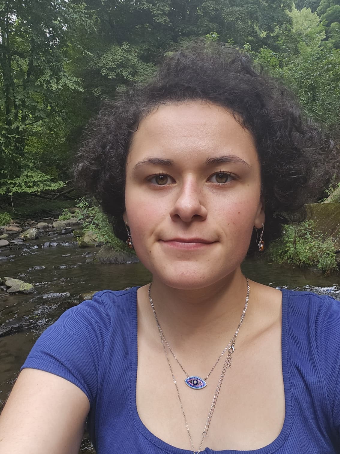 Thalia Toia beside a flowing stream surrounded by trees